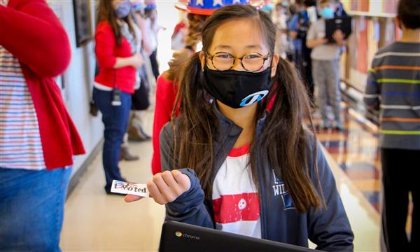 Girl smiles while holding voting sticker
